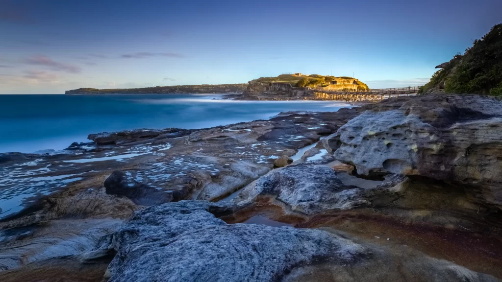 seaside rocky coast sunset calm water pier
