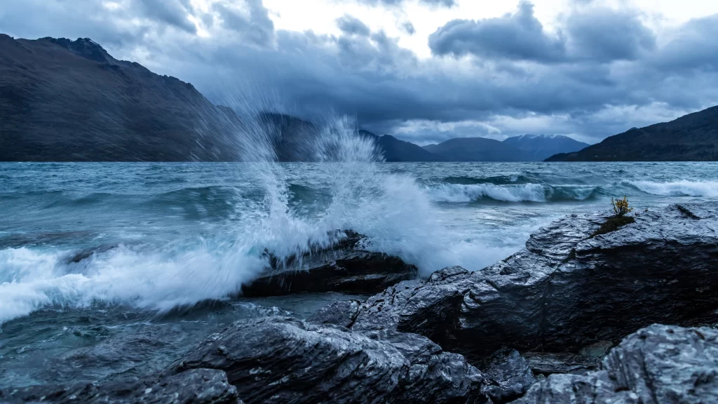 stormy ocean waves rocky shore mountainous landscape dramatic clouds