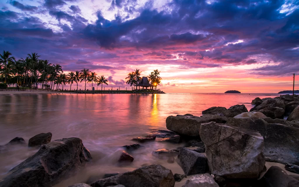Sunset beach rocks palm trees sky clouds