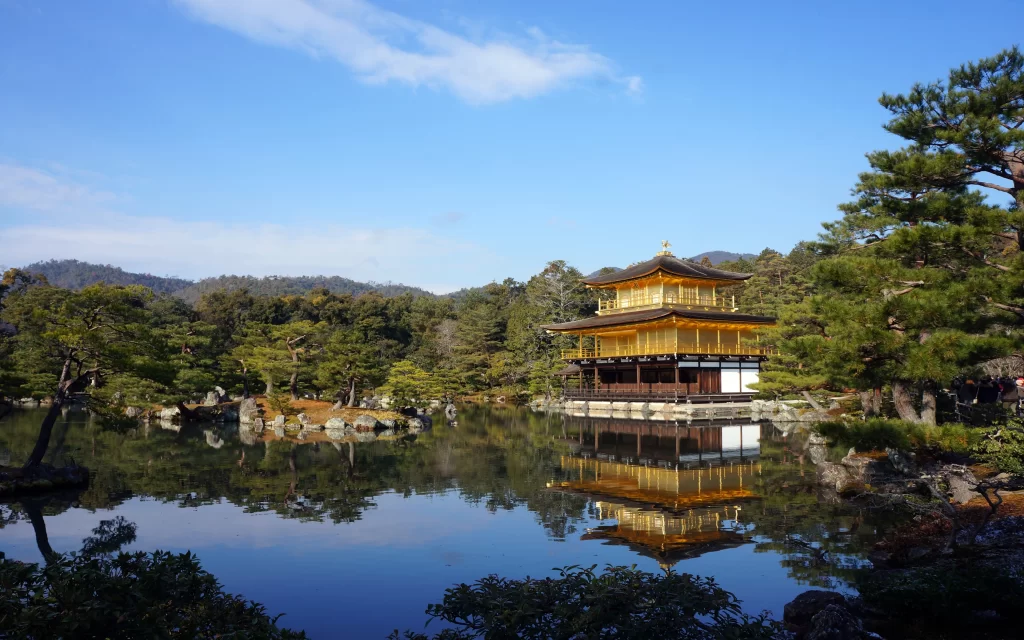 Golden Pavilion Temple Reflective Pond Traditional Architecture Lush Trees Blue Sky Scenic Landscape Kyoto Japan