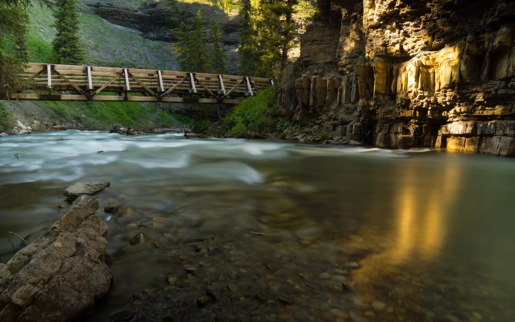 Wooden Bridge Rocky Canyon Flowing River Sunlit Rocks