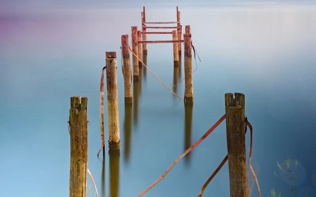 Wooden posts Rusty chains Calm water Reflections
