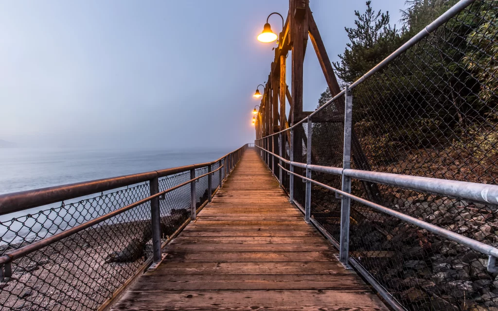 Wooden Pathway Lampposts Misty Atmosphere Rocky Shoreline