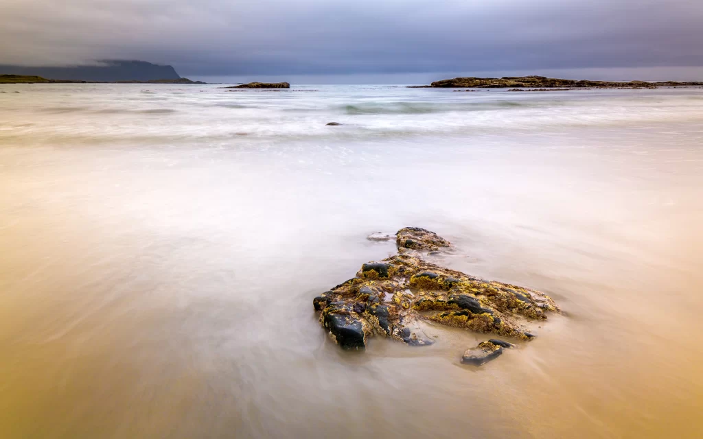 Rocky Shoreline Calm Waters Cloudy Sky Misty Horizon