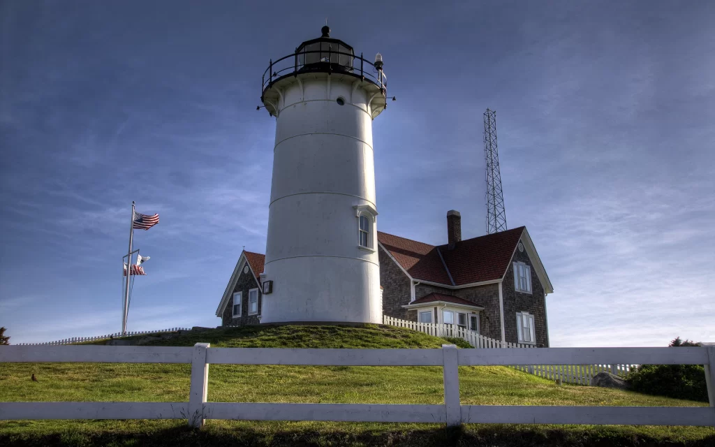 Lighthouse American flag Building White fence Blue sky