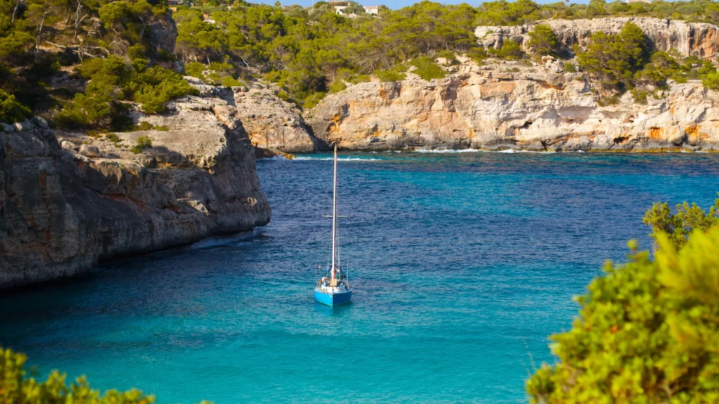 Sailboat Turquoise Water Rocky Coastline Greenery Clear Sky
