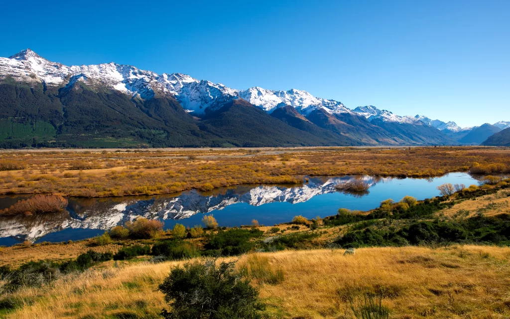 Snow-capped Mountains Clear Blue Sky Reflective Water Golden Grass Autumnal Landscape Tranquil Scenery