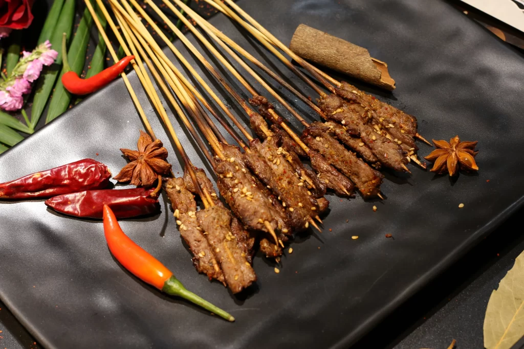 Charred Beef Skewers Spicy Chili Garnish Black Plate