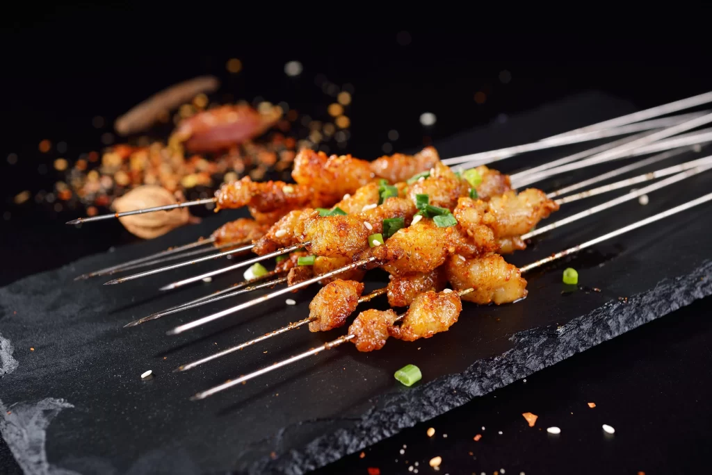 Crispy Pork Skewers Green Onion Garnish Black Slate Plate