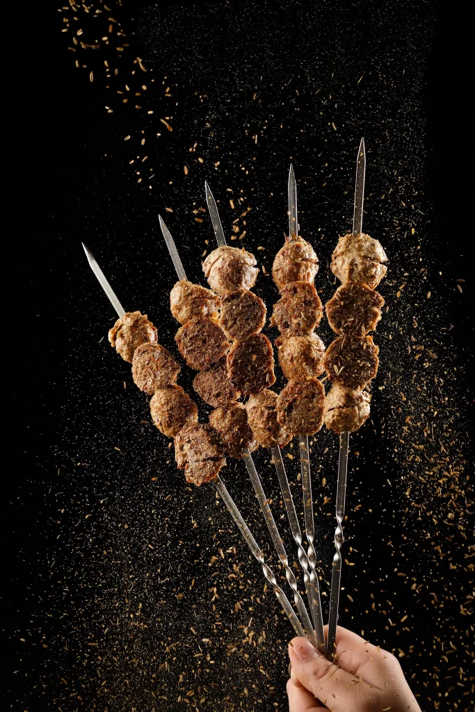 Golden Brown Beef Kabobs with Cumin Garnish on Black Plate