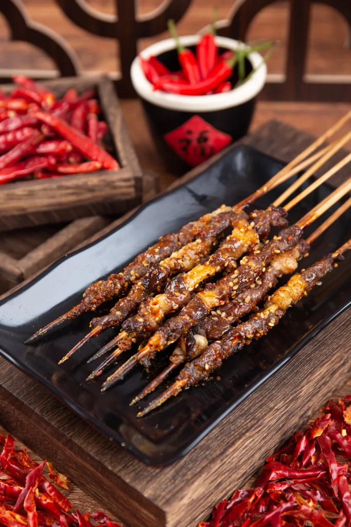 Golden Brown Beef Skewers with Crispy Garlic on Black Plate