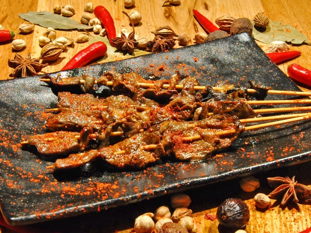 Golden Brown Beef Skewers with Reddish Spice Dust on Black Plate