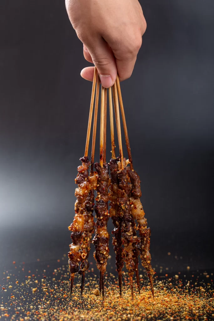 Golden Brown Beef Skewers with Spices on Black Plate