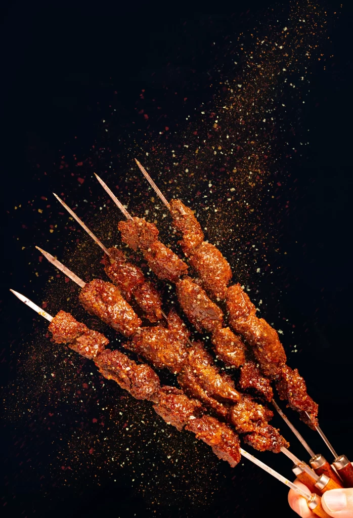 Golden Brown Beef Skewers with Spices on Dark Plate