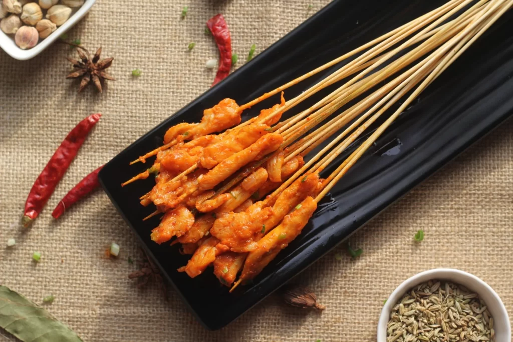 Golden Brown Chicken Skewers on Black Plate with Garnish