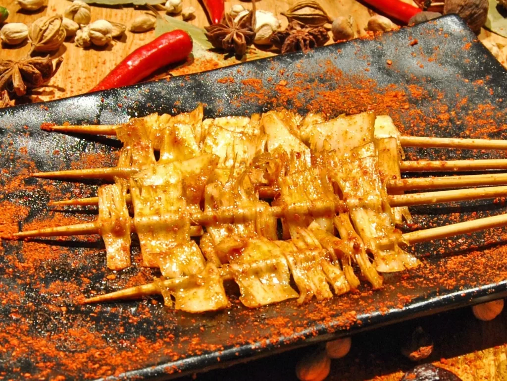 Golden Brown Chicken Skewers on Black Plate with Spices