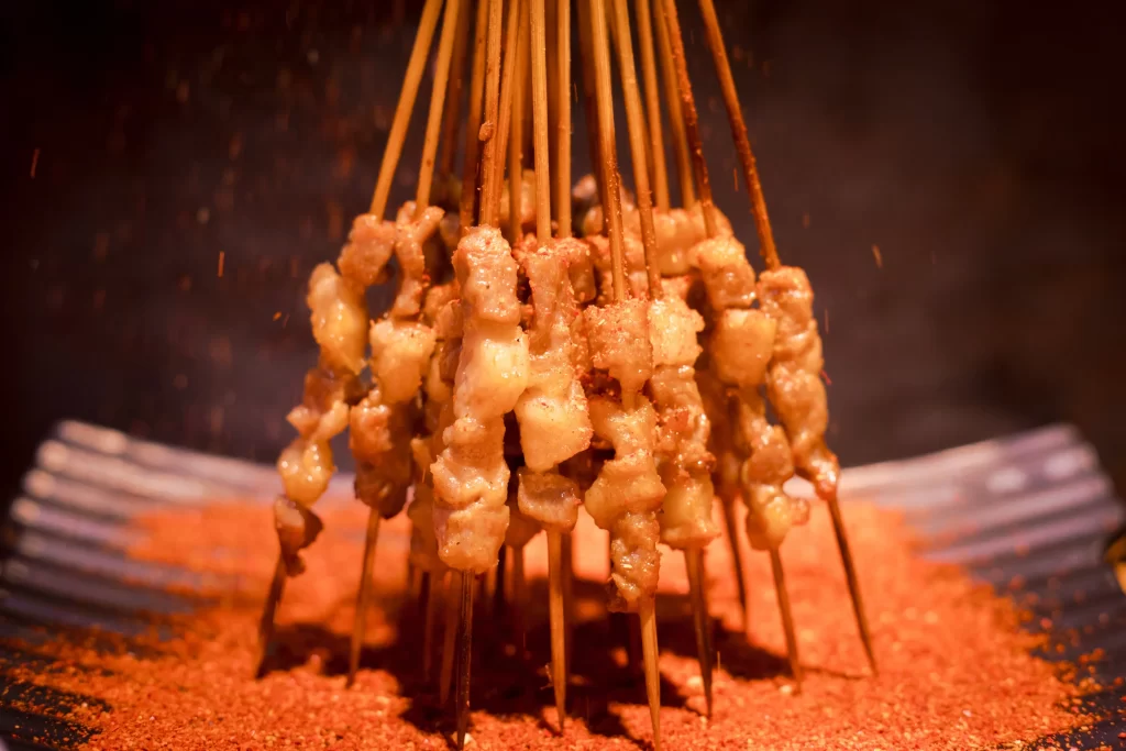 Golden Brown Chicken Skewers on Reddish Spiced Plate