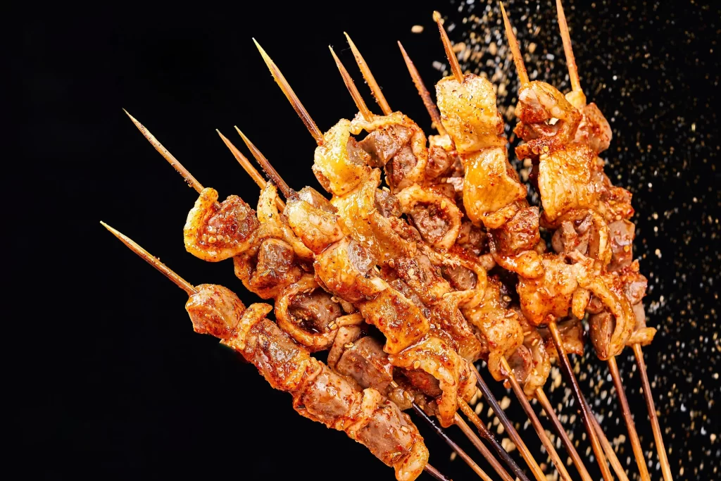 Golden Brown Chicken Skewers with Charred Edges on Black Plate