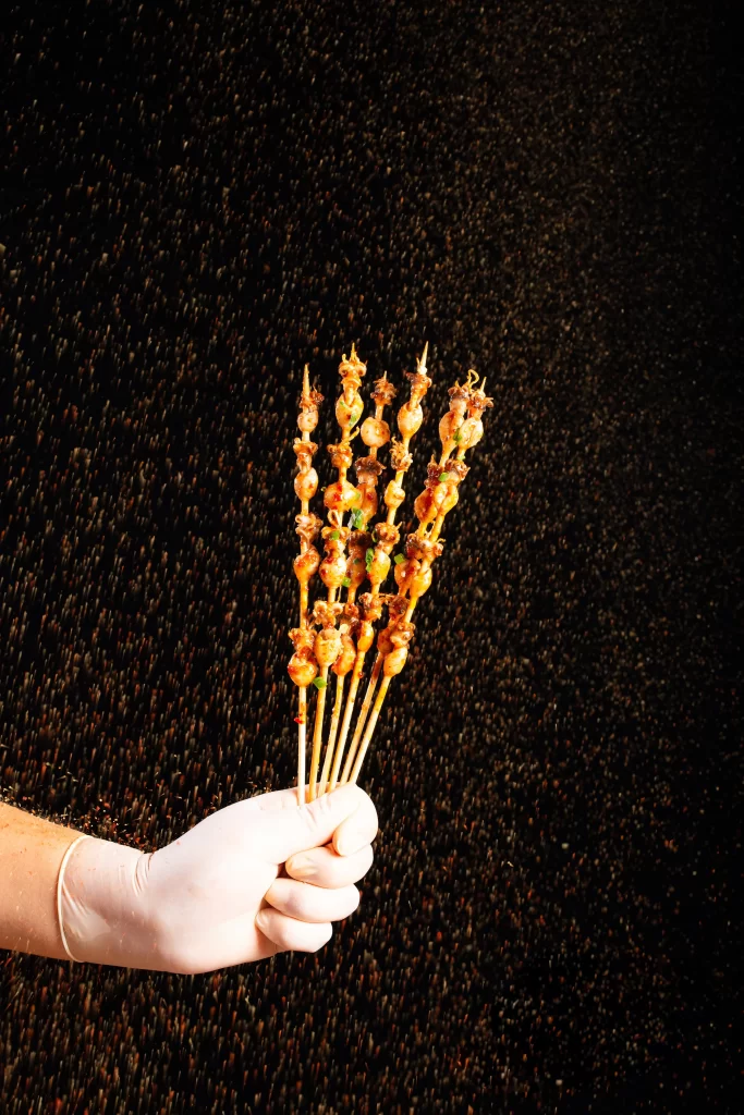 Golden Brown Chicken Skewers with Charred Tips and Green Garnish