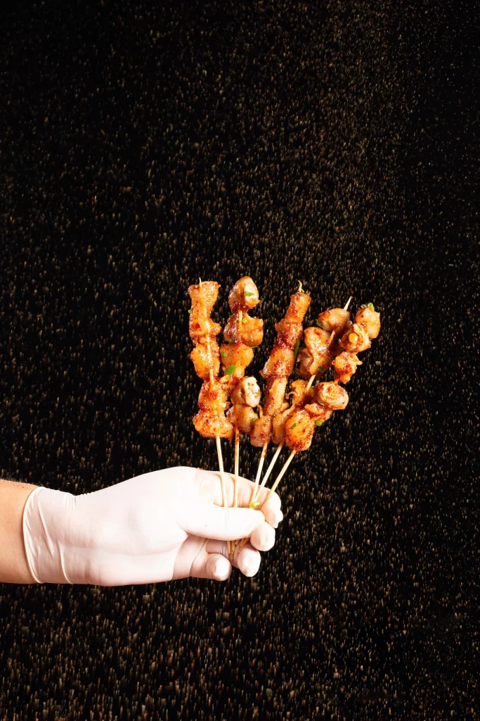 Golden Brown Chicken Skewers with Green Garnish on Dark Plate