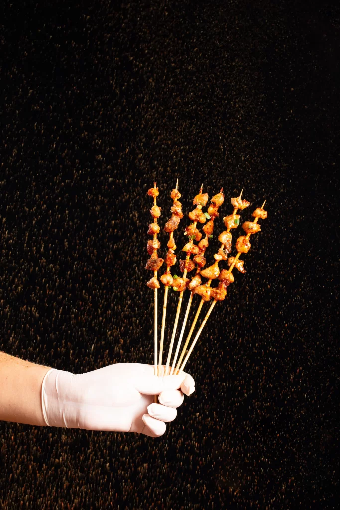 Golden Brown Chicken Skewers with Green Garnish on White Plate