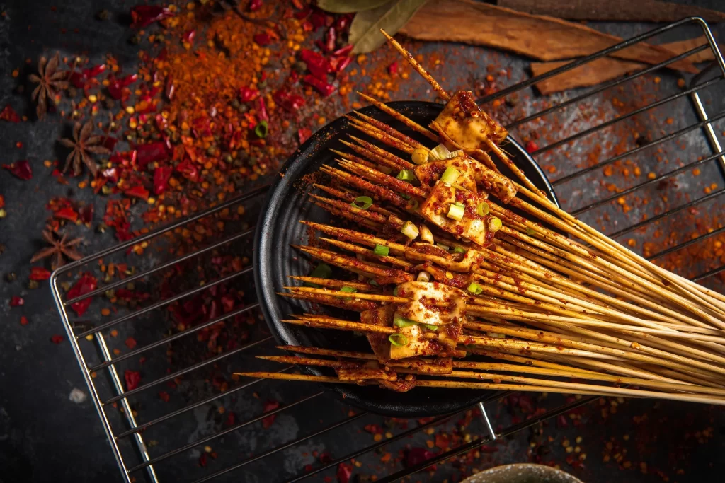 Golden Brown Chicken Skewers with Green Onions on Black Plate