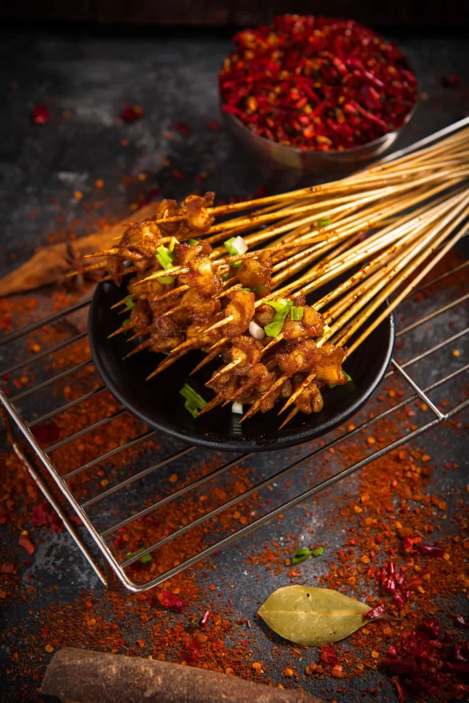 Golden Brown Chicken Skewers with Green Onions on Black Plate
