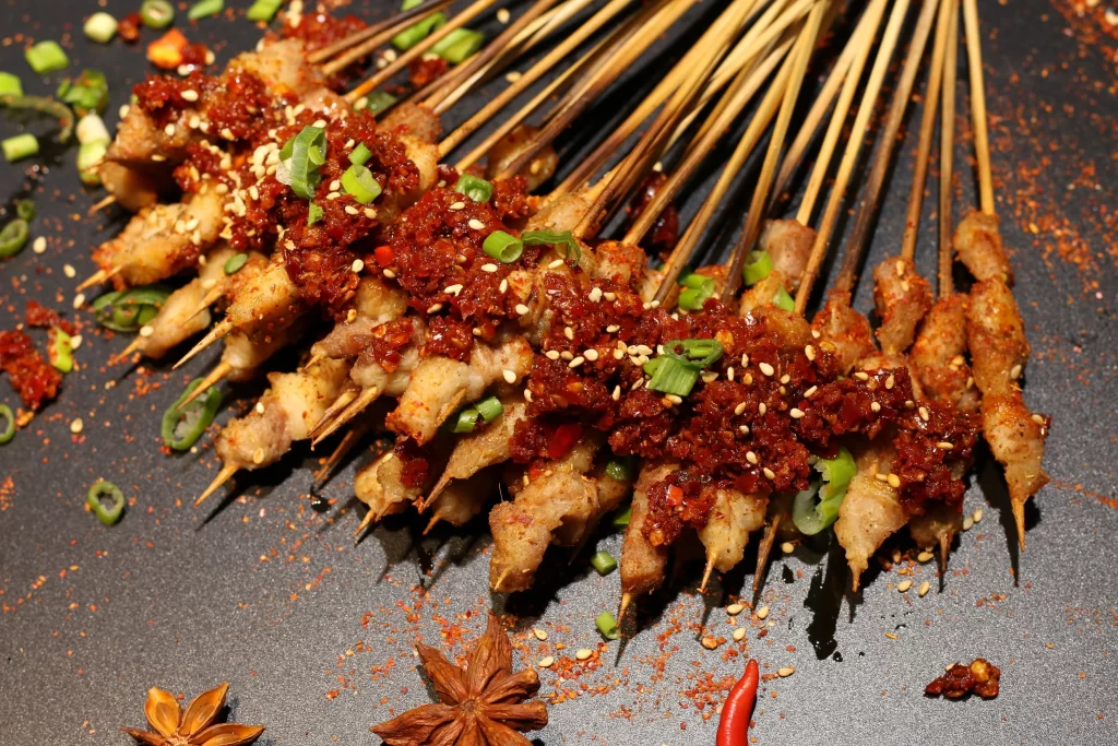 Golden Brown Chicken Skewers with Reddish Sauce and Green Onions