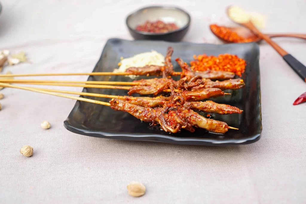 Golden Brown Chicken Skewers with Reddish Spices on Black Plate 012烤鸡爪.J