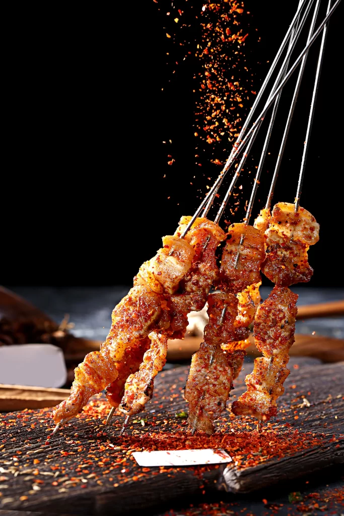 Golden Brown Chicken Skewers with Reddish Spices on Dark Slate