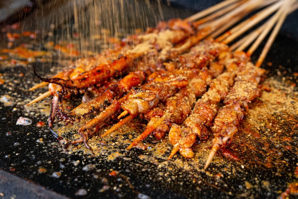Golden Brown Chicken Skewers with Spices on Black Plate