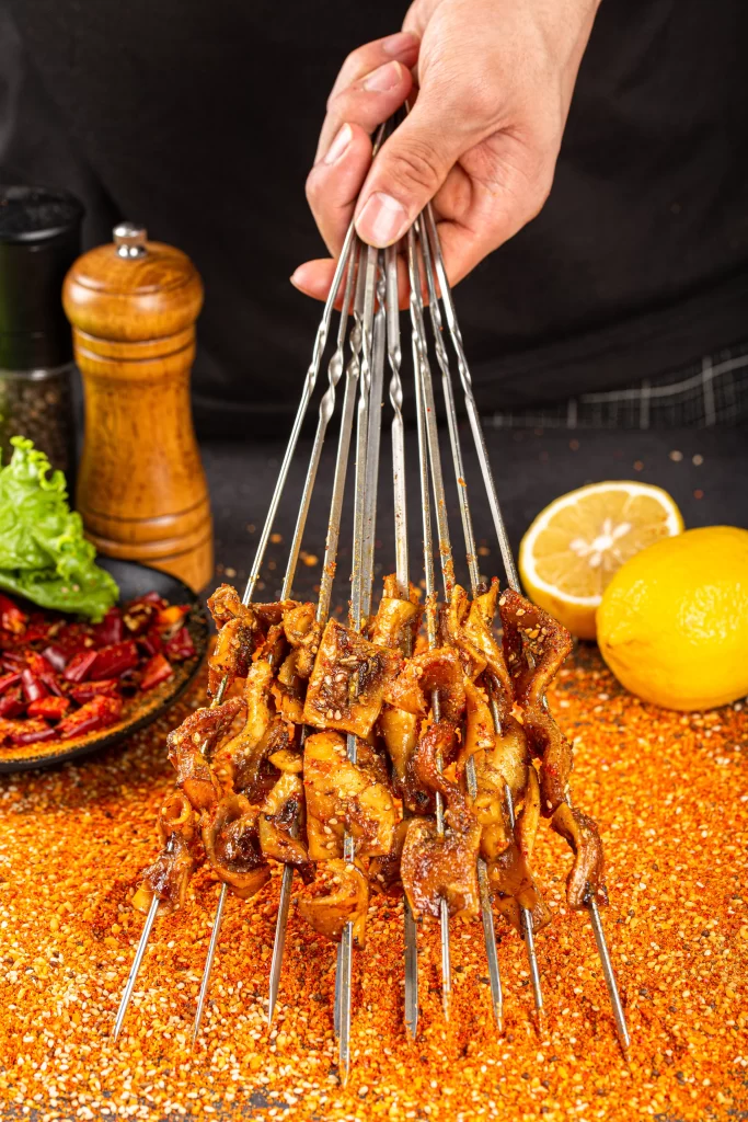 Golden Brown Chicken Skewers with Spices on Black Plate