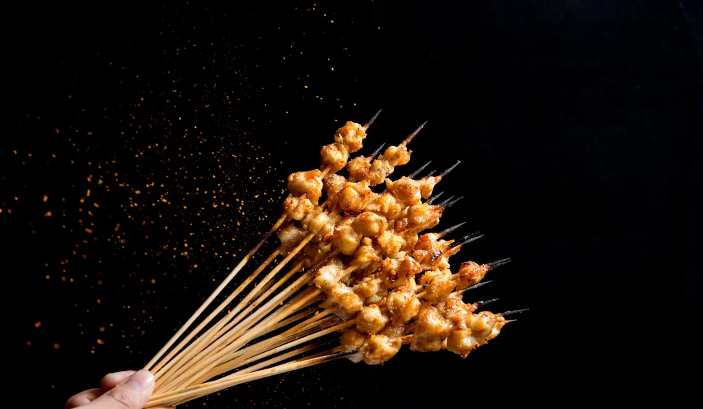 Golden Brown Chicken Skewers with Spices on Dark Plate