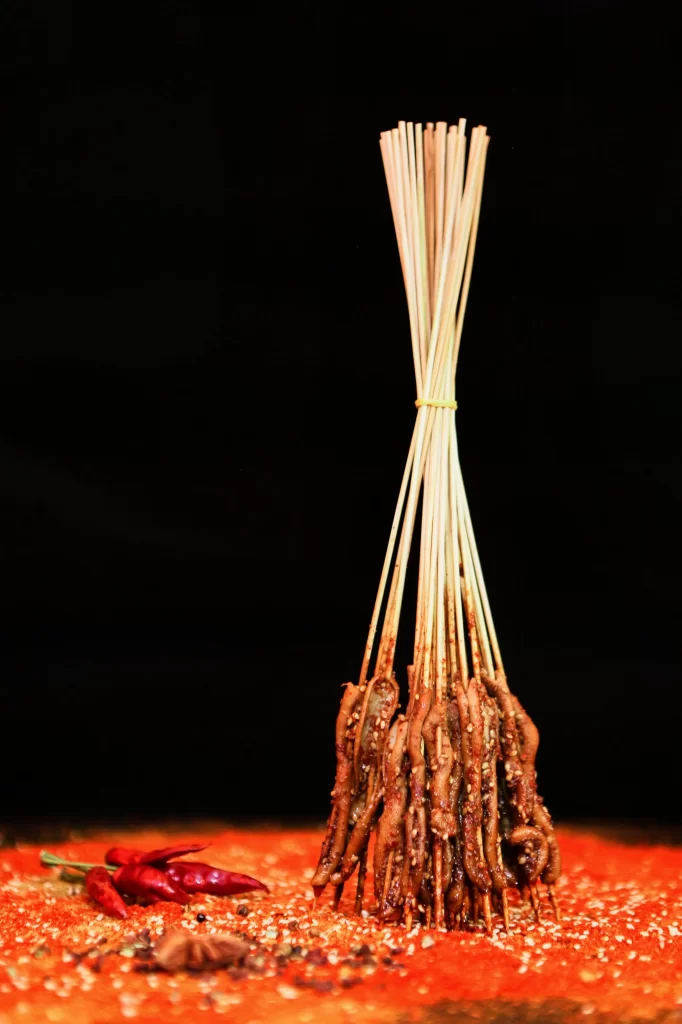 Golden Brown Chicken Skewers with Spices on Red Plate