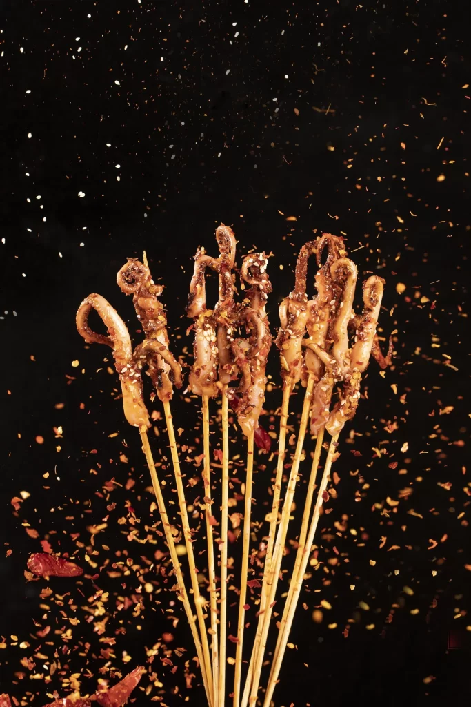 Golden Brown Octopus Skewers with Spices on Dark Background