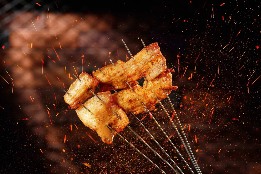 Golden-Brown Pork Ribs Sizzling on Black Charcoal Grill