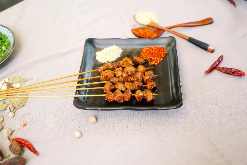 Golden Brown Pork Skewers on Black Plate with Spices 010烤鸡心.J
