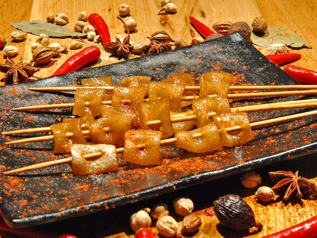 Golden Brown Pork Skewers on Black Rectangular Plate