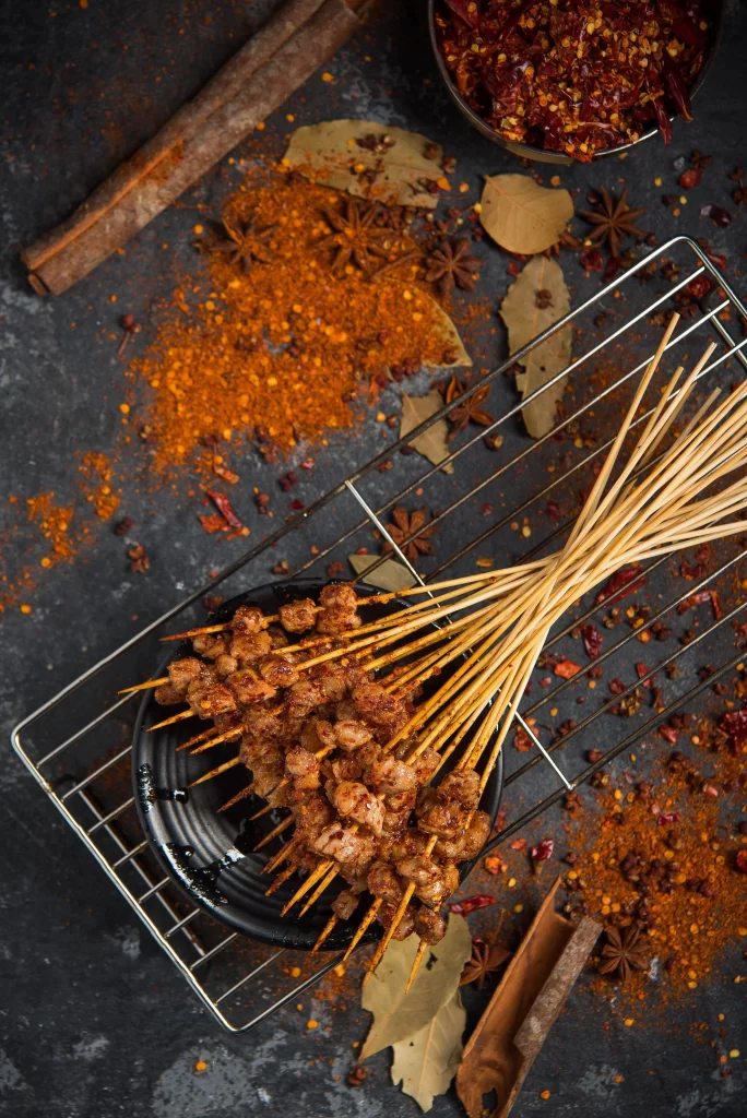 Golden Brown Pork Skewers Resting on Black Plate with Spices (24).JP