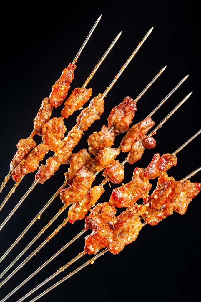 Golden Brown Pork Skewers with Charred Edges and Reddish Sauce