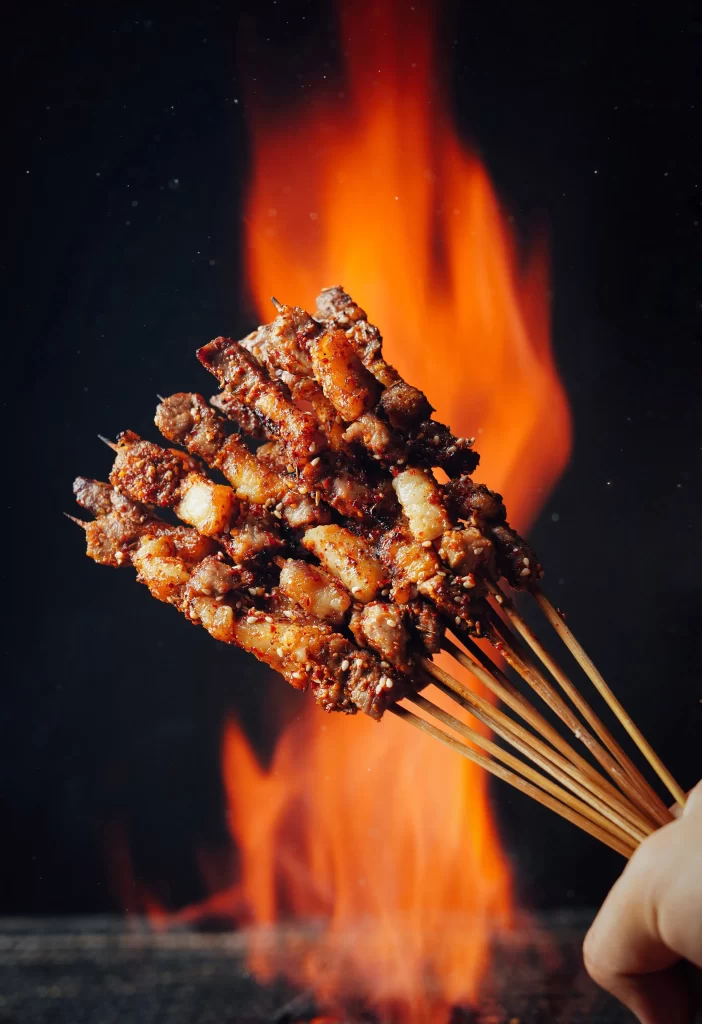 Golden Brown Pork Skewers with Charred Edges and Reddish Sauce