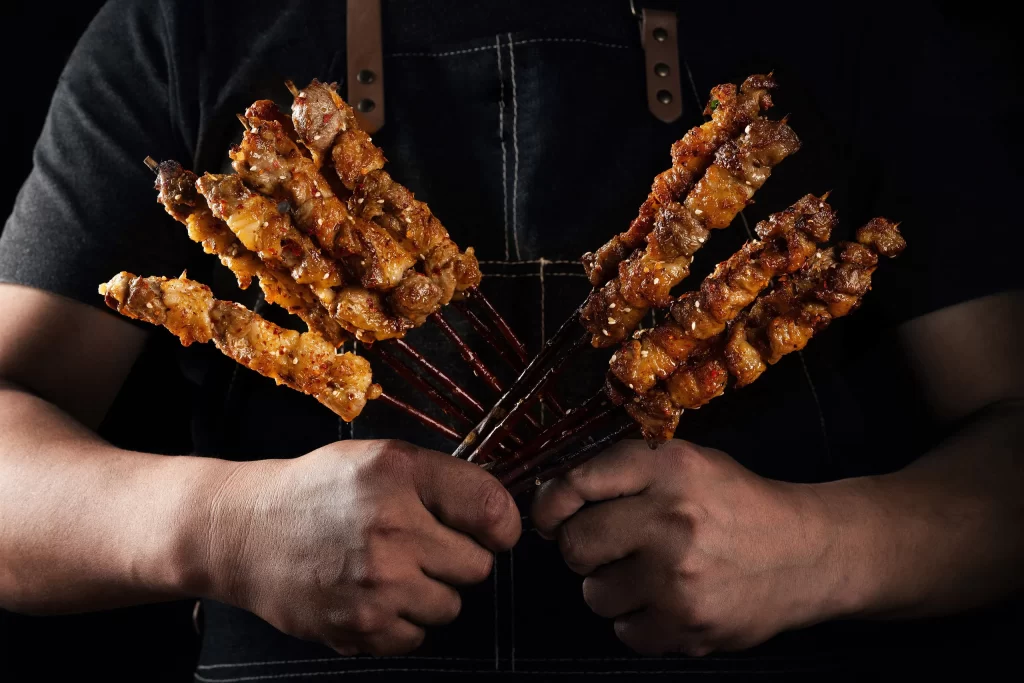 Golden Brown Pork Skewers with Charred Edges and Sesame Garnish
