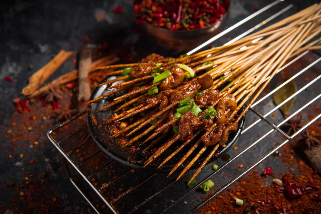 Golden Brown Pork Skewers with Charred Edges on Black Plate
