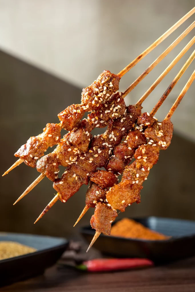 Golden Brown Pork Skewers with Crispy Char and White Sesame Seeds