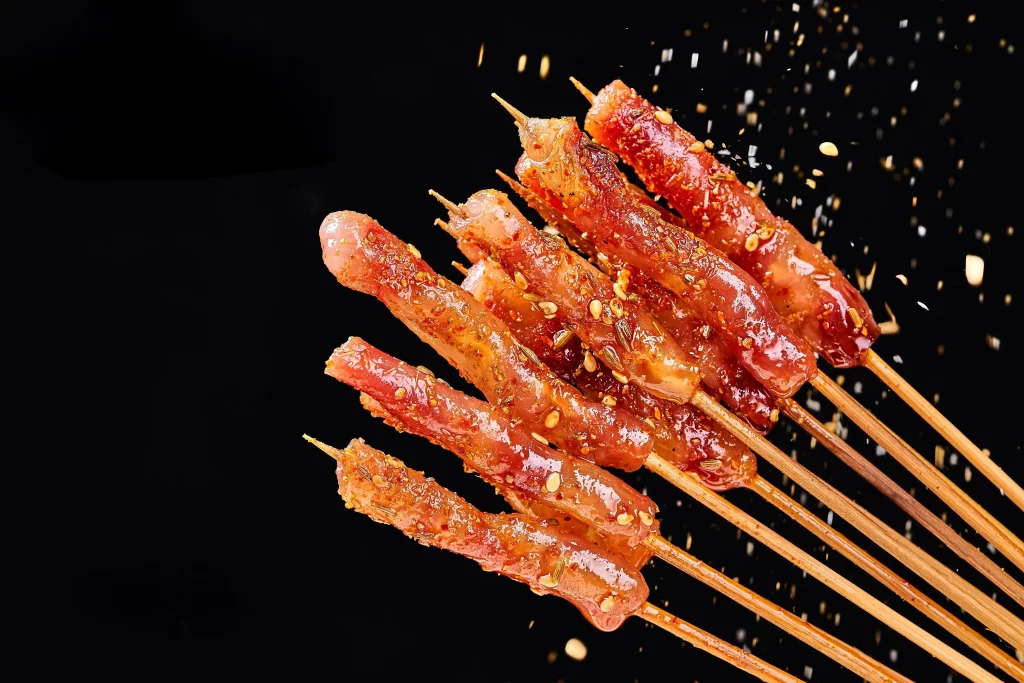 Golden Brown Pork Skewers with Crispy Seasoning on Black Plate