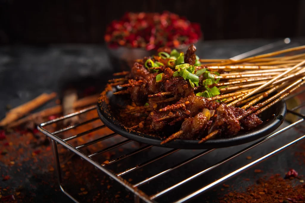 Golden Brown Pork Skewers with Fresh Green Onions on Black Plate