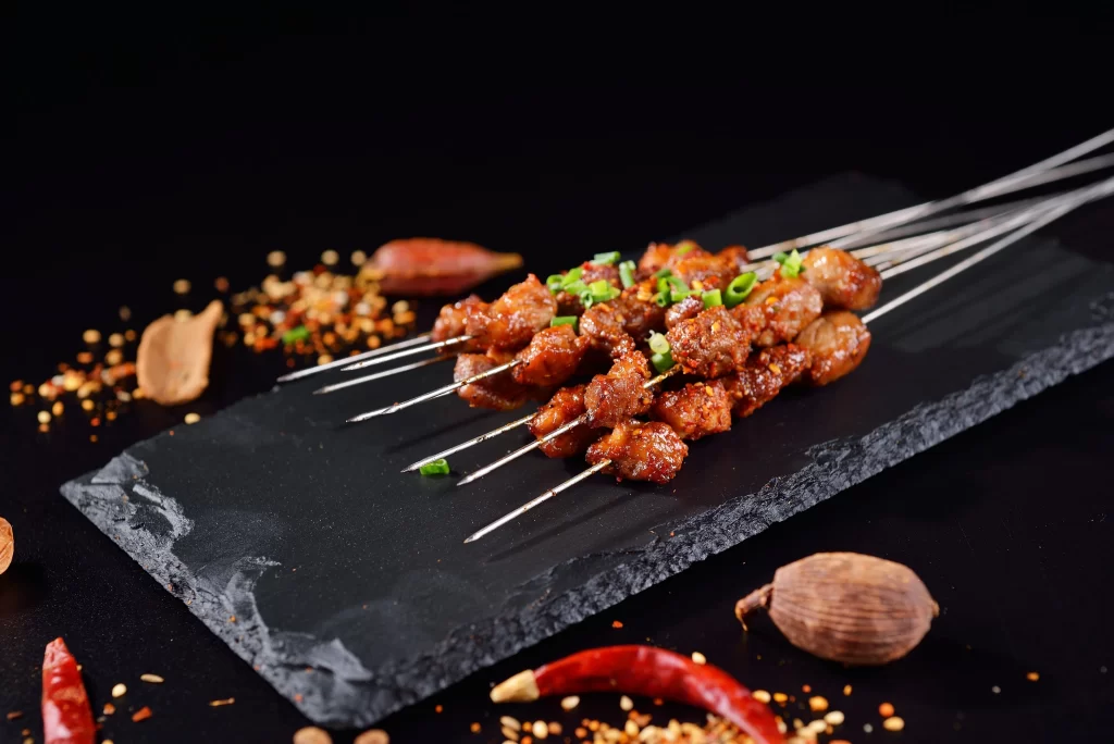 Golden Brown Pork Skewers with Fresh Green Onions on Slate