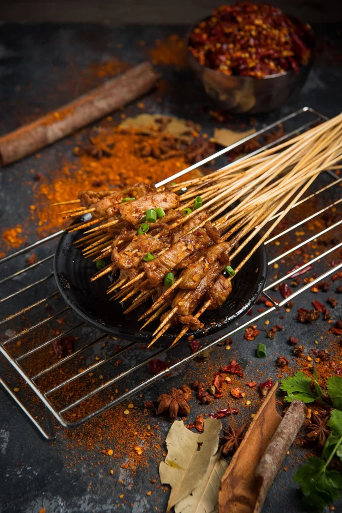 Golden Brown Pork Skewers with Green Onions on Black Plate