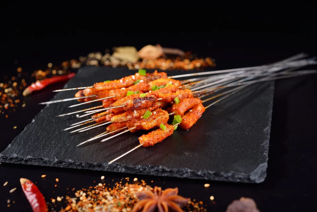 Golden Brown Pork Skewers with Green Onions on Slate Plate