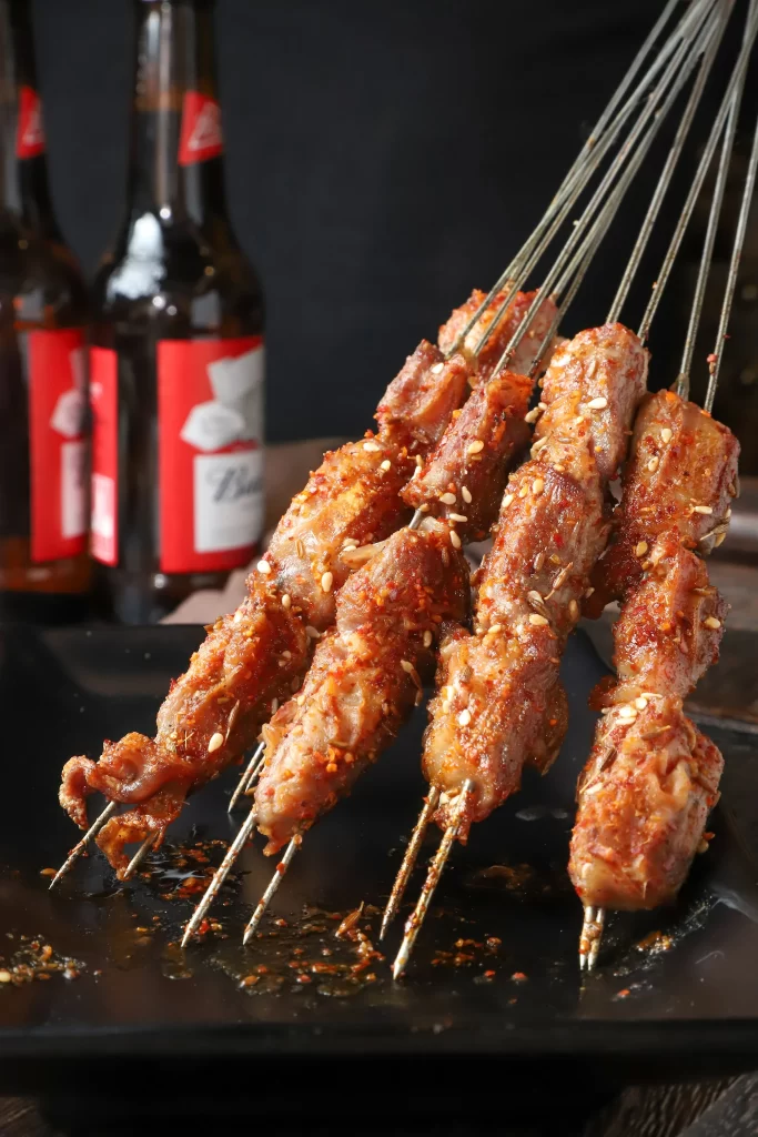 Golden Brown Pork Skewers with Reddish Char and Sesame Garnish